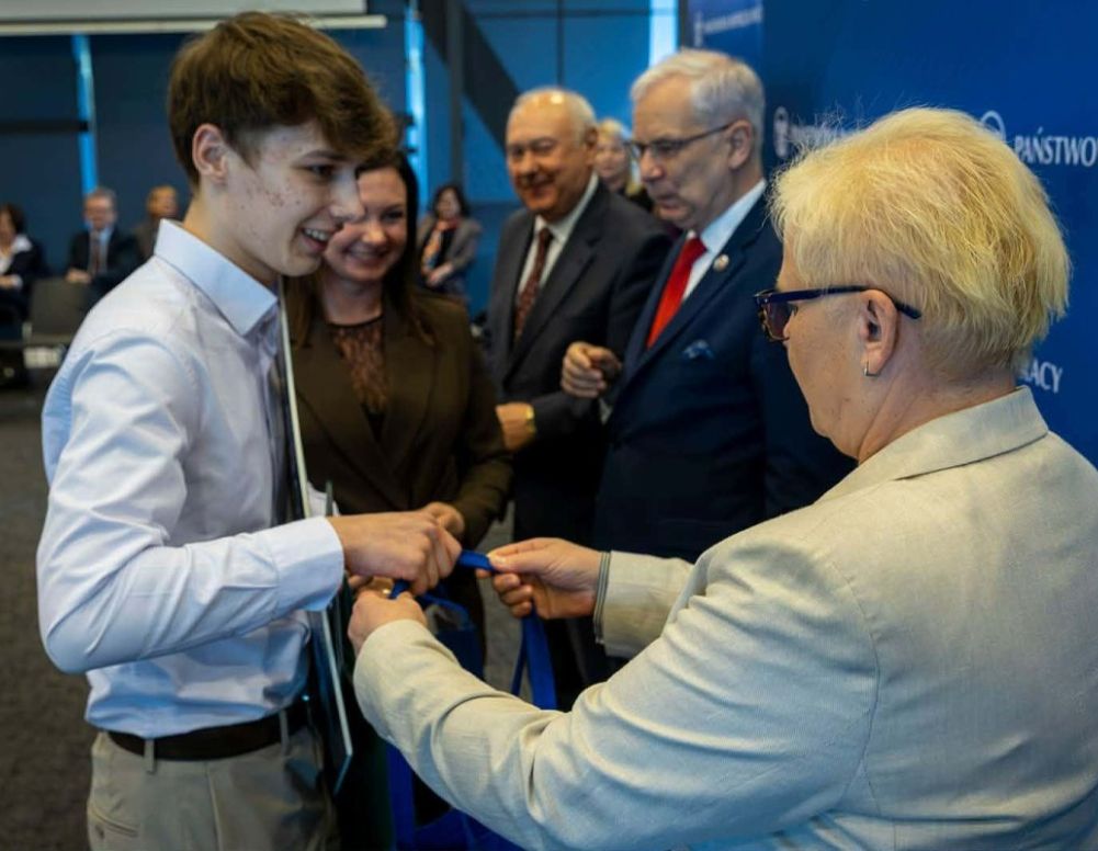 Igor Kanarkiewicz w towarzystwie nauczycielki Edyty Kończal odb9iera nagrodę z rąk organizatorów konkursu